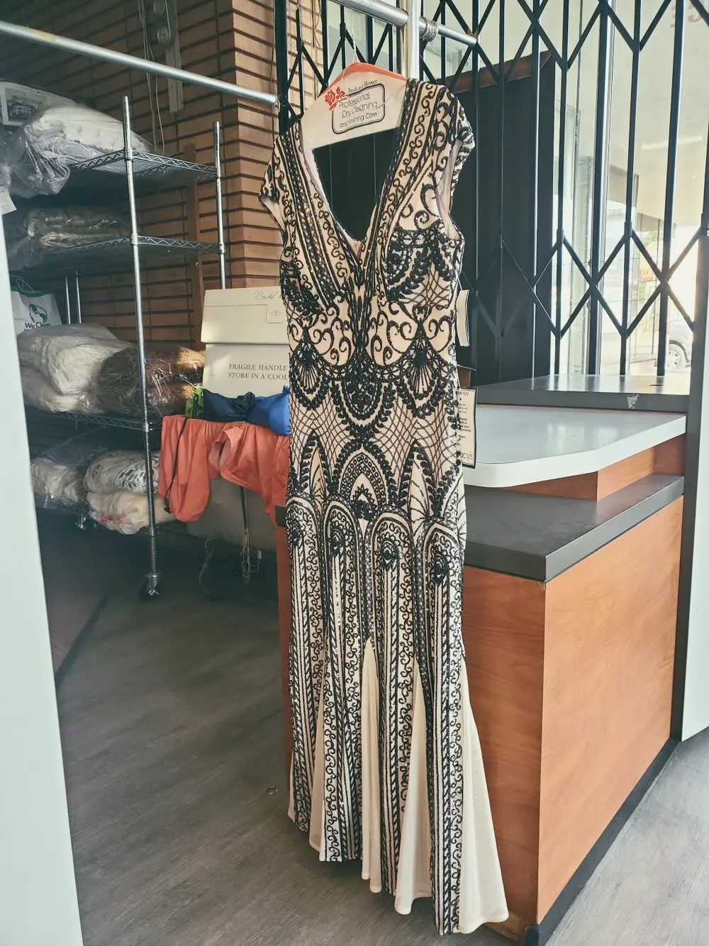Un vestido con pedrería colgado en la tienda, limpio y listo para entregar