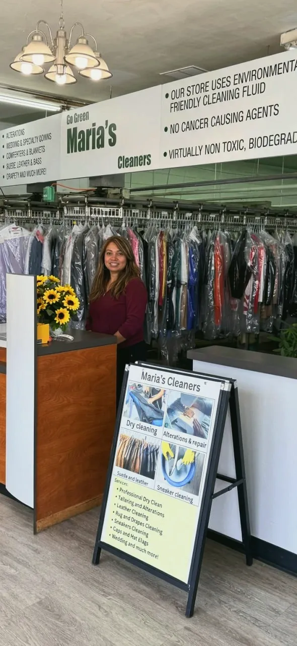 María detrás del mostrador de su tienda, bajo el letrero Go Green