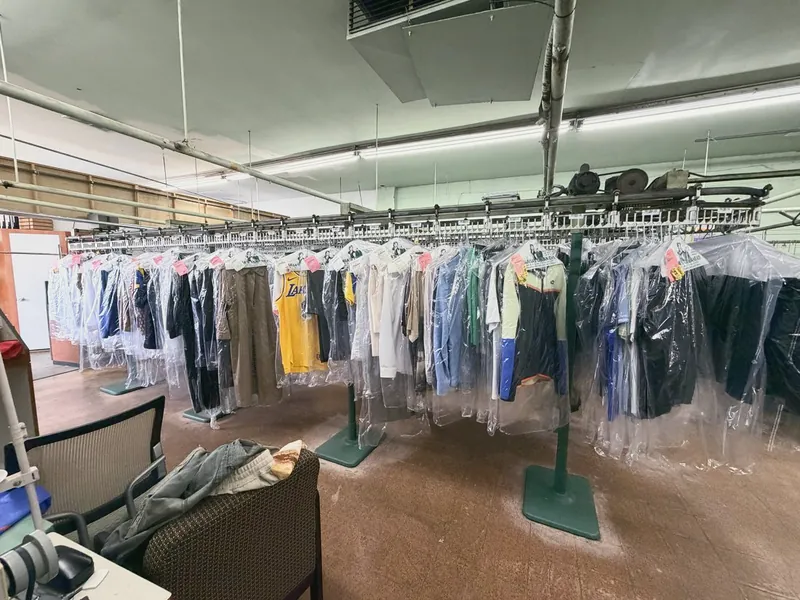 Filas de ropa recién limpia en bolsas de plástico, en el riel de la tienda